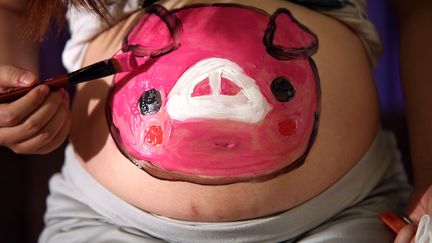 Une femme enceinte a peint un cochon sur son ventre pendant une s&eacute;ance collective de peinture sur corps, &agrave; P&eacute;kin, le 10 septembre 2011. (YANG LE / XINHUA)