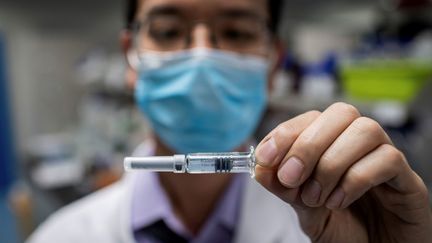 Un ingénieur montre un vaccin expérimental contre le Covid-19 à Pékin, en avril 2020. (NICOLAS ASFOURI / AFP)