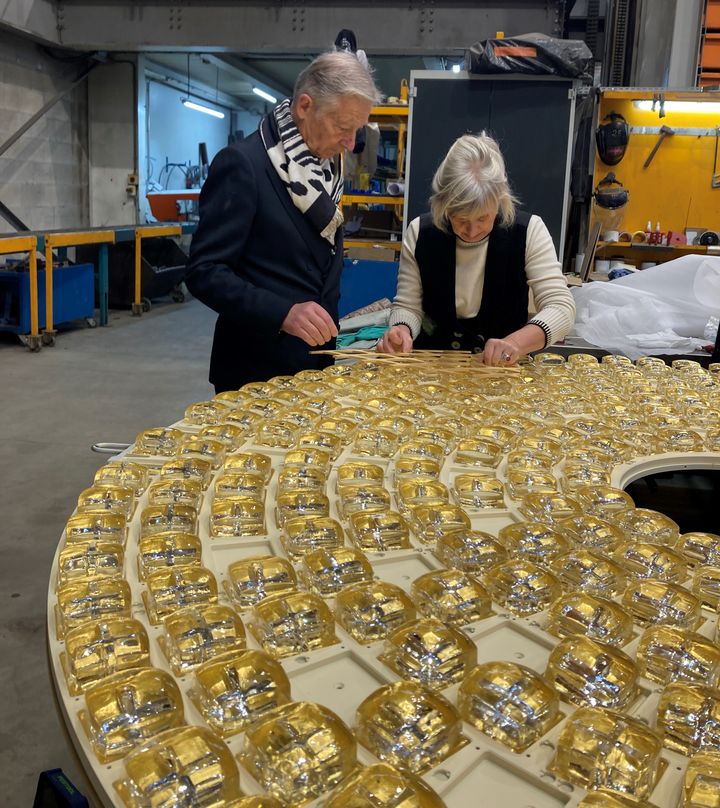 Le designer Sylvain Dubuisson avec Catherine Denoyelle qui finit de fixer les pavés de verre réalisés avec Olivier Juteau pour la châsse reliquaire de Notre-Dame de Paris, le 6 novembre 2024. (VALERIE GAGET / FRANCEINFO CULTURE)