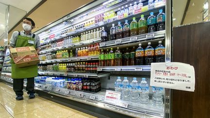 Un employé travaille dans un supermarché, où une pancarte est affichée avec l'inscription "l'eau en bouteille est rationnée, avec un plafond d'une caisse (six bouteilles) par client", dans un supermarché du district de Sumida à Tokyo (Japon), le 10 août 2024. (PHILIP FONG / AFP)