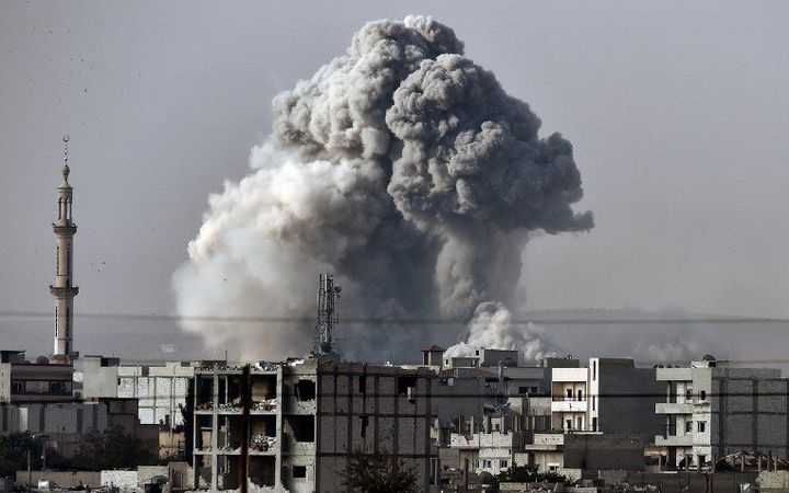 Nuage de fumée à la suite d'un raid américain sur Kobané où les avions de la coalition aident les Kurdes à reprendre la ville aux forces de l'Etat islamique (Daech) (14 octobre 2014). (ARIS MESSINIS / AFP)