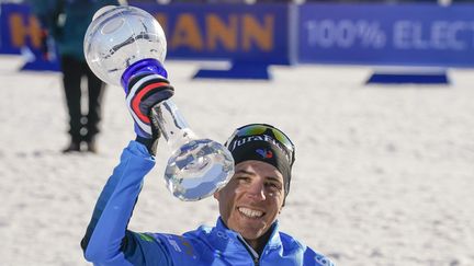 Quentin Fillon Maillet soulève son gros globe de cristal sur le stade d'Oslo-Holmenkollen, le 20 mars 2022. (TERJE BENDIKSBY / NTB / AFP)