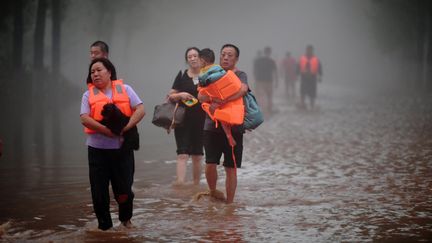 Des habitants sont évacués en raison d'inondations provoquées par le passage d'un typhon à Zhuozhou, en Chine, le 1er août 2023. (ZHAI YUJIA / CNSPHOTO / AFP)