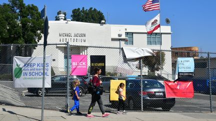 Des passants marchent devant l'auditorium Michael-Jackson de l'école Gardner Street de Los Angeles (Etats-Unis), vendredi 26 avril 2019. Le chanteur avait fréquenté l'établissement pendant quelques mois quand il avait 11 ans. (FREDERIC J. BROWN / AFP)