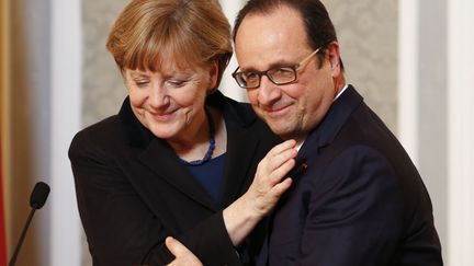 La chanceli&egrave;re allemande Angela Merkel (L) enlace le pr&eacute;sident fran&ccedil;ais Fran&ccedil;ois Hollande lors d'une conf&eacute;rence de presse &agrave; l'issue des n&eacute;gociations de paix portant sur le conflit ukrainien &agrave; Minsk (Ukraine), le 12 f&eacute;vrier 2015. (GRIGORY DUKOR / REUTERS)