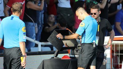 Un arbitre utilise l'assistance arbitrage vidéo lors du match Nîmes PSG en ligue 1, en octobre 2018. (PHOTO PQR / LE PARISIEN /OLIVIER ARANDEL / MAXPPP)