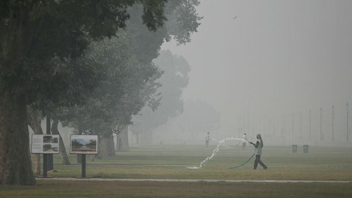 Un ouvrier arrose une pelouse, dimanche 5 novembre 2023, à New Delhi (Inde). (ARUN SANKAR / AFP)