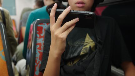 A teenager plays a video game on his phone in the metro in Paris, September 16, 2023. (MYRIAM TIRLER / HANS LUCAS / AFP)