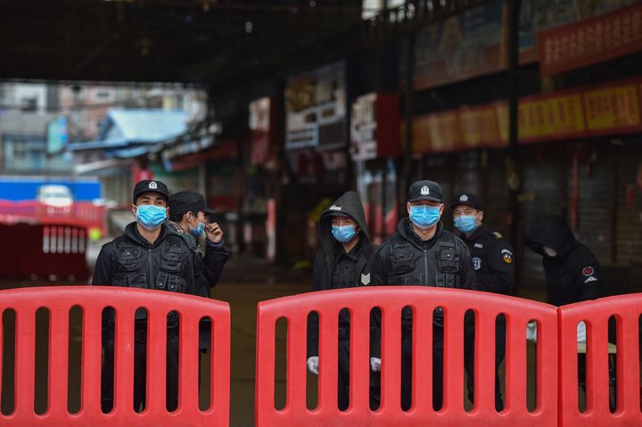 Des policiers gardent l'entrée du marché de gros de fruits de mer de Huanan, à Wuhan (Chine), où le coronavirus a été détecté le 24 janvier 2020, et qui depuis a été fermé par les autorités chinoises.&nbsp; (HECTOR RETAMAL / AFP)