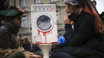 La Suisse n’échappe pas au mouvement. Rassemblés sur la place Paradeplatz à Zurich, où se situe le siège d’UBS, les protestataires posent devant une fausse machine à laver, estampillée du logo de l’organisme financier, l’un des le plus puissants au monde. Pas besoin de slogan, le sang sortant de la machine parle de lui-même. (AFP/FABRICE COFFRINI )