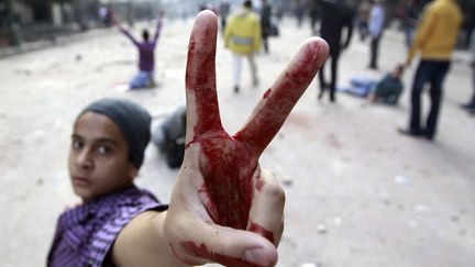 Un jeune manifestant fait le V de la victoire pendant des affrontements avec les forces de l'ordre pr&egrave;s de la place Tahrir au Caire (Egypte), le 16 d&eacute;cembre 2011. (AMR ABDALLAH DALSH / REUTERS)