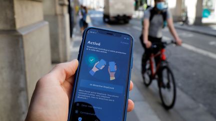 Un homme avec un téléphone dans la main sur lequel est lancé l'application StopCovid, le 27 mai 2020, à Paris.
 (THOMAS SAMSON / AFP)