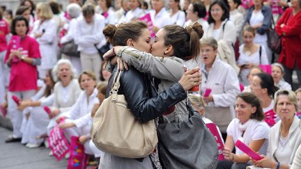 Deux jeunes femmes s'embrassent devant des manifestants d'"Alliance Vita" protestant contre le projet de loi d'ouverture du mariage aux homosexuels &agrave; Marseille (Bouches-du-Rh&ocirc;ne), le 23 octobre 2012. (GERARD JULIEN / AFP)