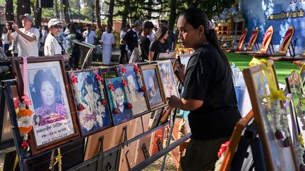 Au parc commémoratif de Ban Nam Khem, en Thaïlande, une femme place le portrait d'un proche. (LILLIAN SUWANRUMPHA / AFP)