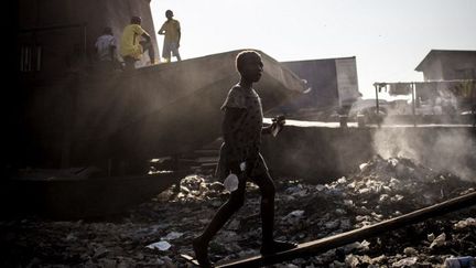 Après avoir acheté un sac d’eau, une jeune Congolaise gravit la rampe d'une embarcation dans un port où des familles vivent dans des bateaux désaffectés le long du fleuve Congo, le 4 juin 2018 à Kinshasa.  (JOHN WESSELS/AFP)