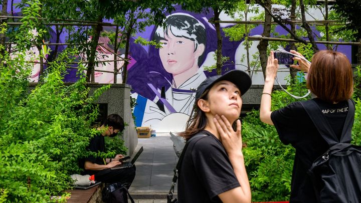 Une fan prend une photo de la peinture murale en l'honneur du groupe BTS, à Séoul, le 12 juin 2023. (ANTHONY WALLACE / AFP)