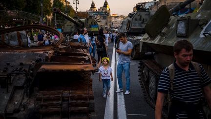 Des personnes regardent des équipements militaires russes détruits dans la rue à Kiev, le 23 août 2022.&nbsp; (DIMITAR DILKOFF / AFP)