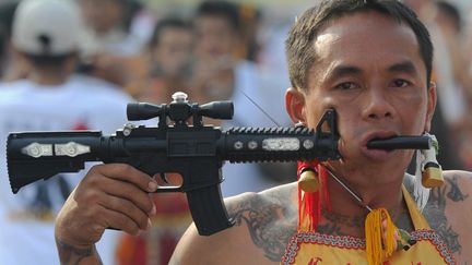 Un fanatique se perce la joue pour expier ses p&ecirc;ch&eacute;s lors du traditionnel festival v&eacute;g&eacute;tarien &agrave; Phuket (Tha&iuml;lande), le 20 octobre 2012. (PORNCHAI KITTIWONGSAKUL / AFP)