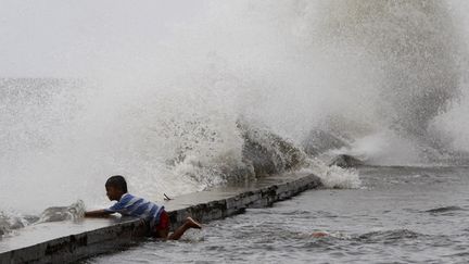 Un enfant s'accroche &agrave; une digue &agrave; Manille, aux Philippines, au passage du "super typhon" Usagi, le 21 septembre 2013.&nbsp; (ROMEO RANOCO / REUTERS)