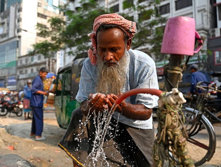 Un conducteur de pousse-pousse se lave le visage au bord de la route lors d'une chaude journée à Dhaka, au Bangladesh, le 15 avril 2024. (STR/NURPHOTO/AFP)