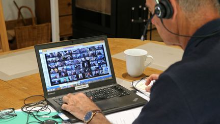 Un homme en télétravail sur la table du salon participe à une vidéoconférence, le 6 mai 2021. (VANESSA MEYER / MAXPPP)