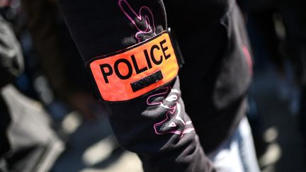 Un homme porte un brassard "police" lors d'une manifestation à l'extérieur du palais de justice de Paris, le 20 avril 2021. (CHRISTOPHE ARCHAMBAULT / AFP)