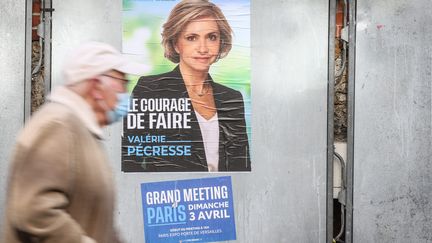 Un homme passe devant une affiche de campagne de Valérie Pécresse, le 10 avril 2022, dans le 15e arrondissement de Paris. (FRED DUGIT / MAXPPP)