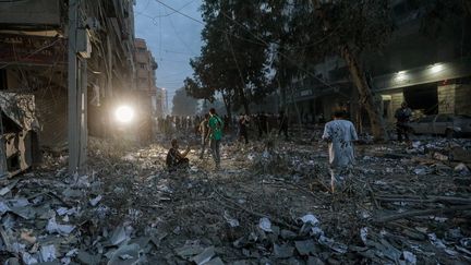 Les Palestiniens inspectent les environs détruits de la Tour Palestine après que des avions de combat israéliens l'ont ciblée dans la ville de Gaza, le 7 octobre 2023, en réponse à l'attaque du Hamas contre Israël. (MOHAMMED SABER / MAXPPP)