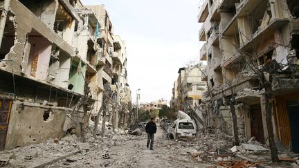 Un homme dans une rue dévastée de la Ghouta orientale, près de Damas, la capitale syrienne, le 25 février 2018. (BASSAM KHABIEH / REUTERS)