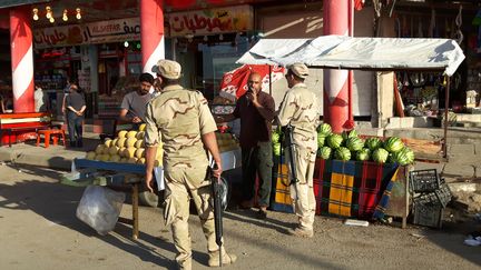 Des soldats devant l'étal d'un vendeur dans les rues de Mossoul-Est. (ALICE SERRANO / RADIOFRANCE)