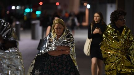 Couvertures de survie sur le dos, ces personnes quittent les lieux visés lors des attaques à Londres (Royaume-Uni), le 3 juin 2017. (CHRIS J RATCLIFFE / AFP)