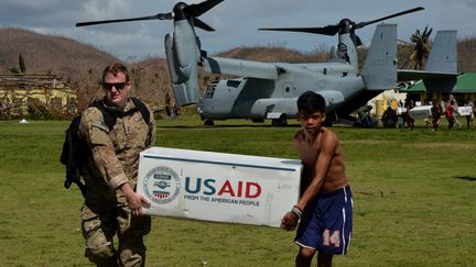 Un soldat am&eacute;ricain aid&eacute; d'un Philippin, victime du typhon Haiyan, d&eacute;charge de l'aide humanitaire &agrave; Balangiga (Philippines), le 16 novembre 2013. (MARK RALSTON / AFP)