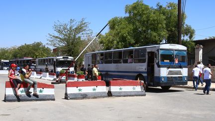 Des bus transportant des familles syriennes passent un check point, à l'entrée de Qadam, dans le sud de Damas (Syrie), le 21 août 2014. (YOUSSEF KARWASHAN / AFP)