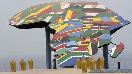 Un homme lit un journal devant une carte de l'Afrique sur la Place du Souvenir Africain, à Dakar, le 27 janvier 2016 (SEYLLOU / AFP)