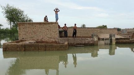 Des personnes touchées par les inondations attendent des secours dans la province du Pendjab, au Pakistan, le 29 août 2022. (SHAHID SAEED MIRZA / AFP)