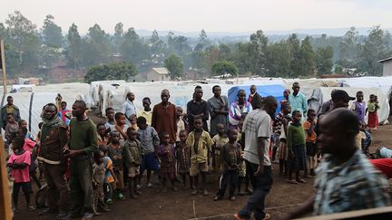 Des réfugiés se tiennent devant des tentes dans un camp de personnes déplacées&nbsp;à l'extérieur de la ville de Bunia, dans la province d'Ituri (République démocratique du Congo), le 21 juin 2019. (SAMIR TOUNSI / AFP)