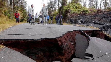 Des journalistes et des soldats face à une route endommagée par l'éruption du volcan Kilauea, à Hawaï, le 18 mai 2018. (TERRAY SYLVESTER / REUTERS)