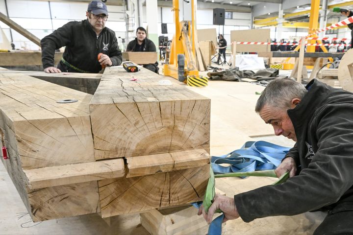 Des charpentiers travaillent sur le bois du socle de la nouvelle flèche de Notre-Dame de Paris, à Briey, en Lorraine, le 16 mars 2023. (JEAN-CHRISTOPHE VERHAEGEN / AFP)