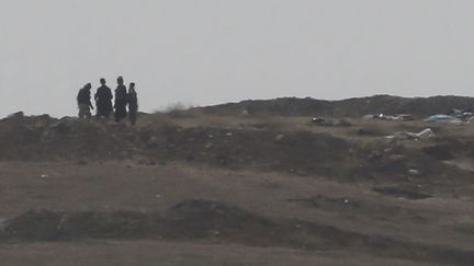 Des combattants, probablement membres du groupe Etat islamique, photographi&eacute;s &agrave; l'ouest de Kobani (Syrie), le 13 octobre 2014. (UMIT BEKTAS / REUTERS)