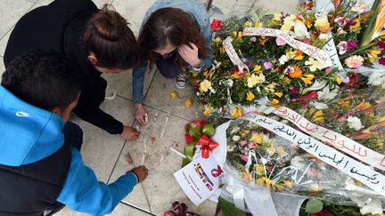 Des touristes allument des bougies devant le mus&eacute;e du Bardo &agrave; Tunis, en hommage aux victimes de l'attaque, le 27 mars 2015. (FETHI BELAID / AFP)