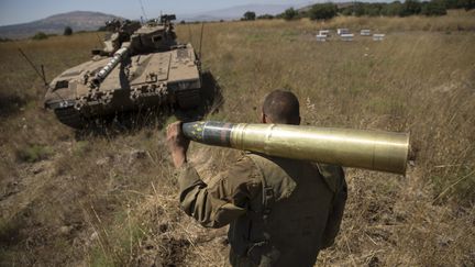 Un soldat isra&eacute;lien porte un obus, dans la r&eacute;gion du Golan occup&eacute;e par Isra&euml;l, le 22 juin 2014. (BAZ RATNER / REUTERS)