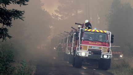 Une colonne de camions de pompiers se forme au bord d&rsquo;une route, le vendredi 24 juillet. Les lances &agrave; incendie sont pr&ecirc;tes &agrave; asperger d&rsquo;eau le sol br&ucirc;lant. Pr&egrave;s de 400 pompiers luttent sans rel&acirc;che contre les flammes. (TARIS PHILIPPE / MAXPPP)