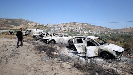 Un Palestinien regarde des voitures brûlées à Naplouse en Cisjordanie, après une attaque de colons israéliens, le 21 juin 2023. (ISSAM RIMAWI / ANADOLU AGENCY / AFP)