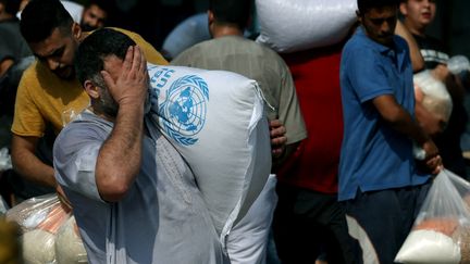 Des Palestiniens collectent des sacs de légumineuses séchées dans un centre géré par l'ONU à Deir al-Balah (Gaza), le 28 octobre 2023. (MOHAMMED ABED / AFP)