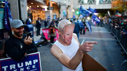 Un supporteur de Donald Trump portant un masque en carton à l'effigie du candidat démocrate Joe Biden tance des manifestants anti-Trump, devant un bureau où sont comptés les bulletins de vote, à Philadelphie, jeudi 5 novembre 2020.&nbsp; (MARK MAKELA / REUTERS)