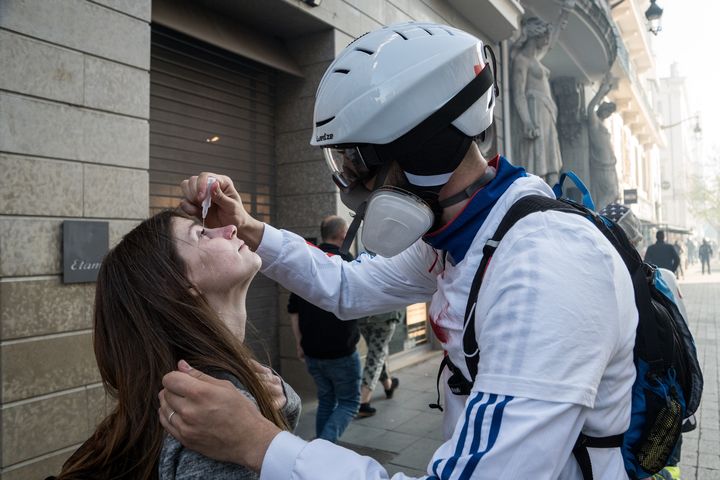 Un "street medic" met du sérum&nbsp;physiologique dans les yeux d'une femme, lors d'une manifestation des "gilets jaunes", le 23 mars 2019 à Lyon. (NICOLAS LIPONNE / NURPHOTO / AFP)