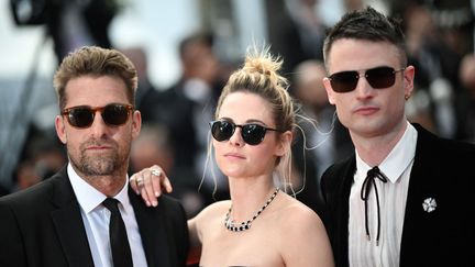 Kristen Stewart est encadré par ses deux gardes du corps, les acteurs Scott Speedman et Tom Sturridge, caché derrière leurs lunettes de soleil. (LOIC VENANCE / AFP)