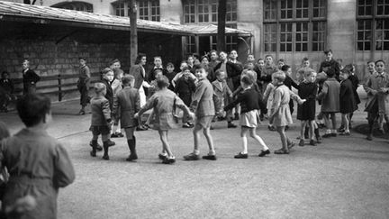 Des écoliers font une ronde à la récré le jour de la rentrée des classes le 1er octobre 1947 (AFP - Hélier)