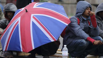  (Un migrant érytrhéen s'abrite sous un parapluie, le 27 mai à Calais © REUTERS / Pascal Rossignol)