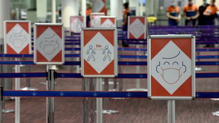 Des panneaux informatifs le long d'une file d'attente dans le terminal 2E de l'aéroport Roissy-Charles de Gaulle, le 18 mars 2021. (ERIC PIERMONT / AFP)